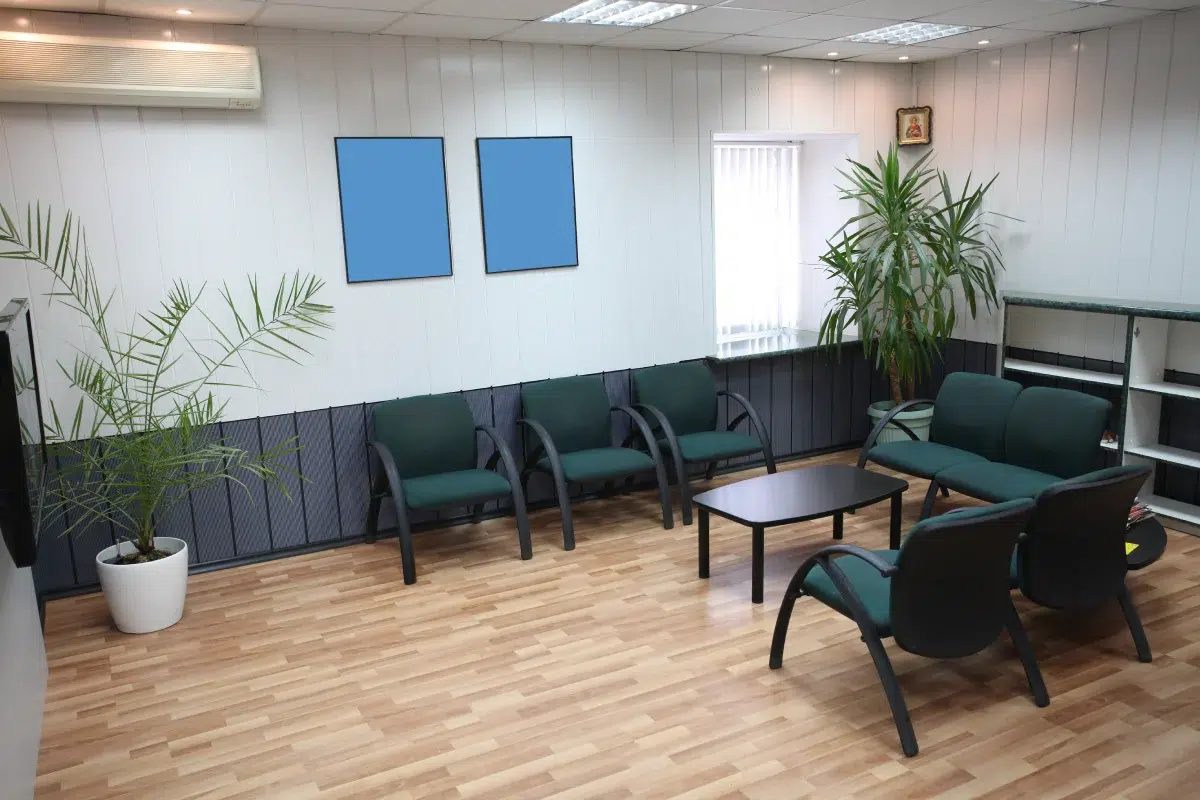 Salle d'attente moderne avec plantes et chaises.