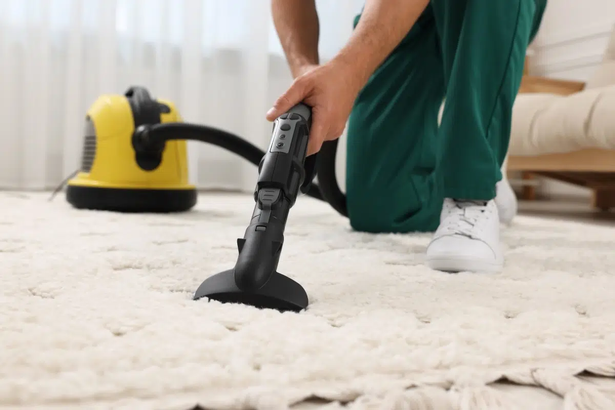Nettoyage de tapis avec aspirateur Personne passant l'aspirateur sur un tapis blanc